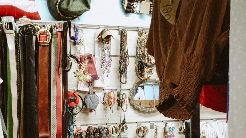 İkinci el dükkânında askıda kıyafetler, kemerler ve aksesuarlar